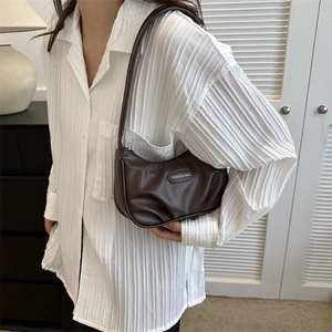 Sac à bandoulière plissé marron foncé minimaliste avec lettrage porté par un mannequin