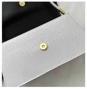 Dettaglio della borsa in pelle goffrata bianca con chiusura magnetica dorata e fodera nera