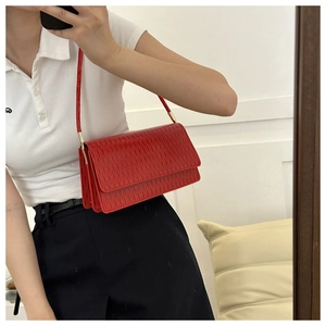 Dettaglio ravvicinato di una borsa a tracolla rossa testurizzata con patta classica chic
