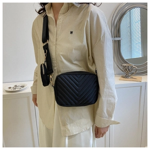 Dettaglio borsa a tracolla trapuntata nera con tracolla larga e una mini pochette rotonda