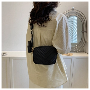Dettaglio della borsa nera trapuntata con cuciture a V e astuccio sulla tracolla