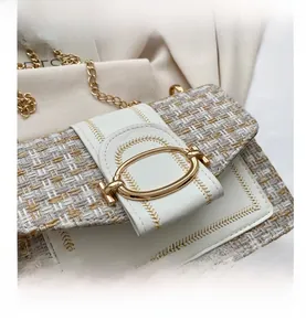 Detail der gewebten Tweed-Umhängetasche mit weißer Lederklappe und goldener Schnalle
