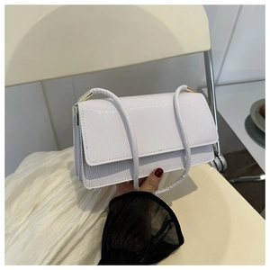 Dettaglio della pelle sintetica bianca a trama coccodrillo su borsa con accessori dorati