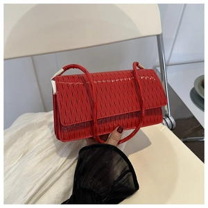 Dettaglio della borsa a spalla rossa con texture a pieghe e accenti metallici