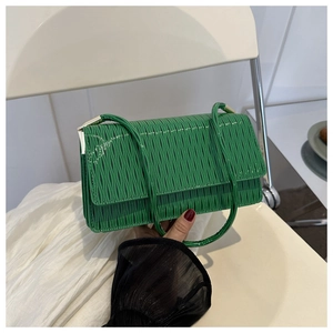 Dettaglio della borsa a tracolla verde con trama a onde verticali lucida e tracolla