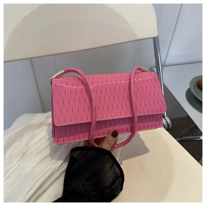 Dettaglio della borsa rosa con texture a pieghe, finitura lucida e fibbia dorata fine
