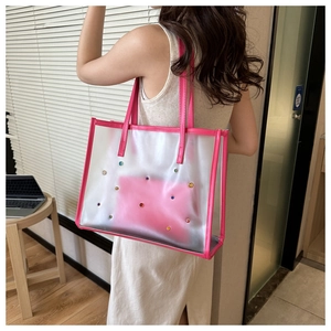Detail of transparent PVC tote bag with pink leather trim and colorful rhinestone studs