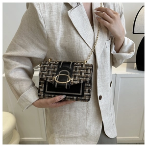 Detail einer Tweed-Umhängetasche mit Goldschließe auf einem beigen Leinen-Blazer