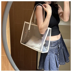 Close-up of transparent PVC jelly tote bag featuring colorful rhinestone accents and white trim