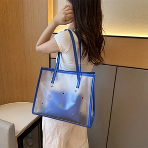 Blue PVC tote bag with colorful crystals and inner pouch shown on model