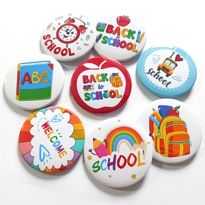Close-up of vibrant Back to School tinplate badges with cartoon school bus and apple designs