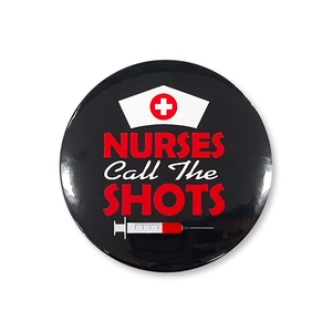Macro detail of Nurses Call The Shots tinplate badge with syringe and nurse hat graphics