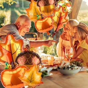 Outdoor family dinner with autumn Thanksgiving balloons including pumpkin and maple leaf shapes