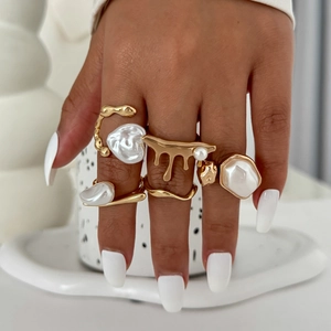 Detailed shot of irregular liquid metal rings set featuring elegant Baroque pearls on hand