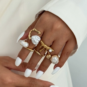 Detail of baroque pearl rings with melted gold metal design on model's hand