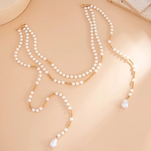 Detail of layered pearl body chain with golden pins and baroque pearl pendant
