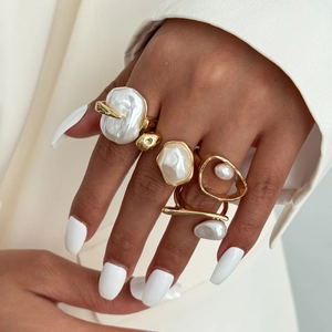 Detail of baroque pearl rings on hand with elegant gold irregular metal band design
