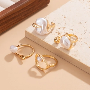 Detail of gold-plated rings set featuring baroque pearls on a rustic stone display