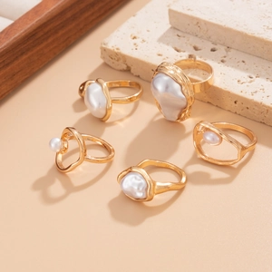 Artistic detail of gold baroque pearl ring set on minimalist beige travertine decor