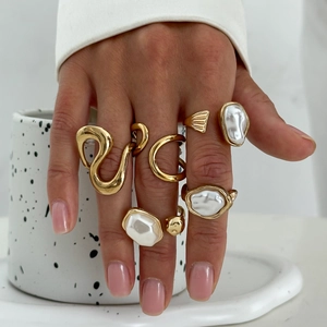 Detailed view of irregular gold rings set with baroque pearls on a model's hand