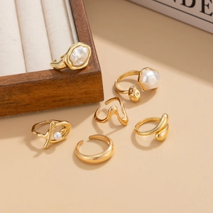 Detail view of a 6-piece gold ring set featuring baroque pearls and minimalist lava designs