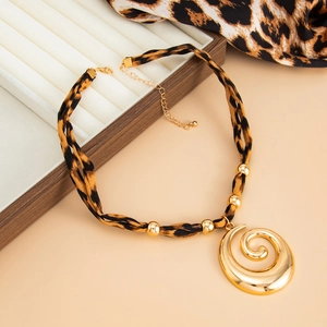 Leopard print fabric necklace with large gold spiral heart pendant on beige background