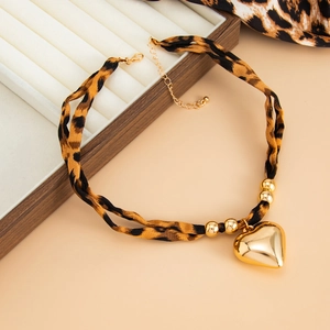 Detail of leopard print fabric necklace featuring a large polished gold heart pendant