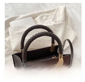 Detail of retro tote bag featuring brown woven handle and gold hardware on book background
