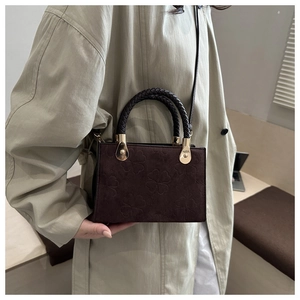 Detail of vintage clover embossed chocolate crossbody bag with woven handle and gold hardware