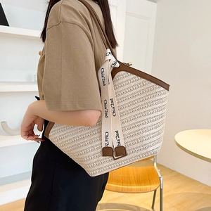 Vintage straw tote bag with brown leather handles and decorative ribbon for summer