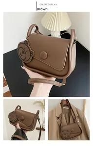 Close-up of brown PU saddle bag with a cute bear charm and elegant matte finish texture