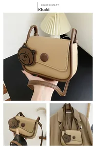 Close-up of khaki retro saddle bag with round snap button and cute bear charm detail