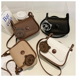 Flat lay of multiple color small square PU leather bags with bear charms on white table