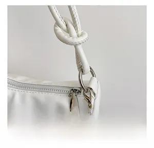 Gros plan de la boucle argentée et du fermoir mousqueton sur un sac en cuir blanc