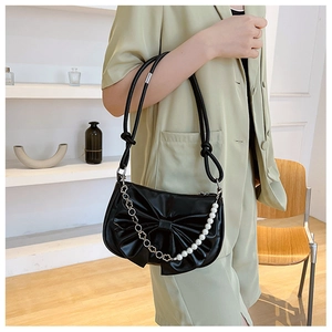 Détail du sac à bandoulière noir avec nœud, perles et élégants accents floraux en métal