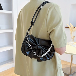 Sac à épaule noir avec grand nœud plissé et chaîne en perles porté par un mannequin