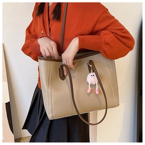 Detail of minimalist tote bag with color-block straps and a cute plush monster charm