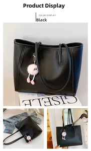 Detail of large black tote bag featuring a pink plush monster charm and smooth PU leather
