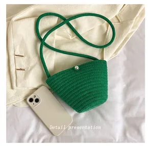 Détail macro du sac seau tissé vert avec perle et référence de taille de téléphone