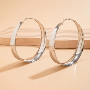 Macro detail of silver flat hoop earrings with polished mirror finish on a wooden tray