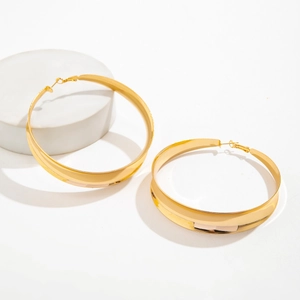 Macro shot of chunky gold hoop earrings with polished flat metal surface on a white stand