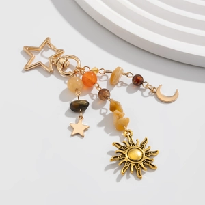 Detail of golden celestial keychain featuring sun, moon, and star charms with beads