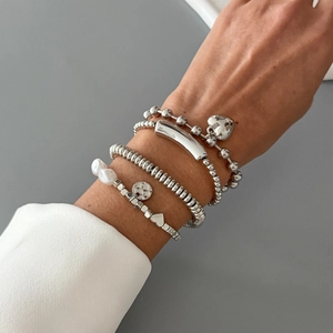 Layered silver bracelet set with Virgin Mary pendant and pearls on a female wrist