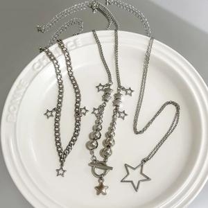 Close-up of silver star pendant necklaces with OT buckle on white ceramic plate