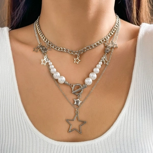 Close-up of a layered silver necklace with baroque stars and white pearls on a model