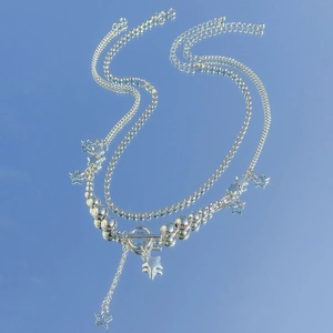 Detail of layered silver necklace featuring hollow star pendants and a toggle OT clasp
