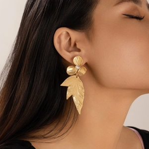 Detail of golden ginkgo leaf and flower earrings with pearls on a female model