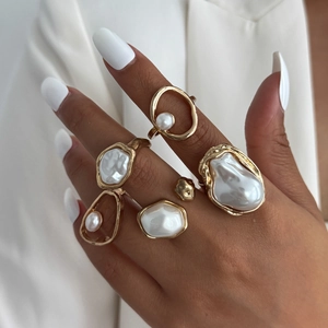 Five-piece set of golden irregular rings featuring baroque pearls on a female hand
