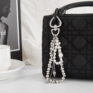Perlen-Taschenkette mit Herzverschluss und Kunstperlen an einer schwarzen Stepptasche