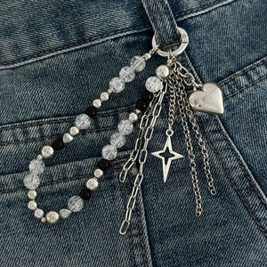 Detail der mehrlagigen Hosenkette mit Herz- und Sternanhänger auf Denim